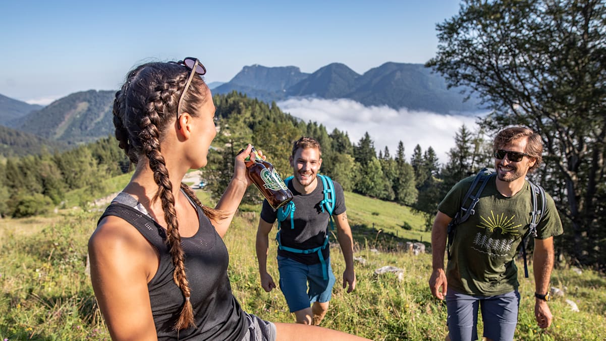 Ein Bier in der Hand einer Frau auf der Alm.