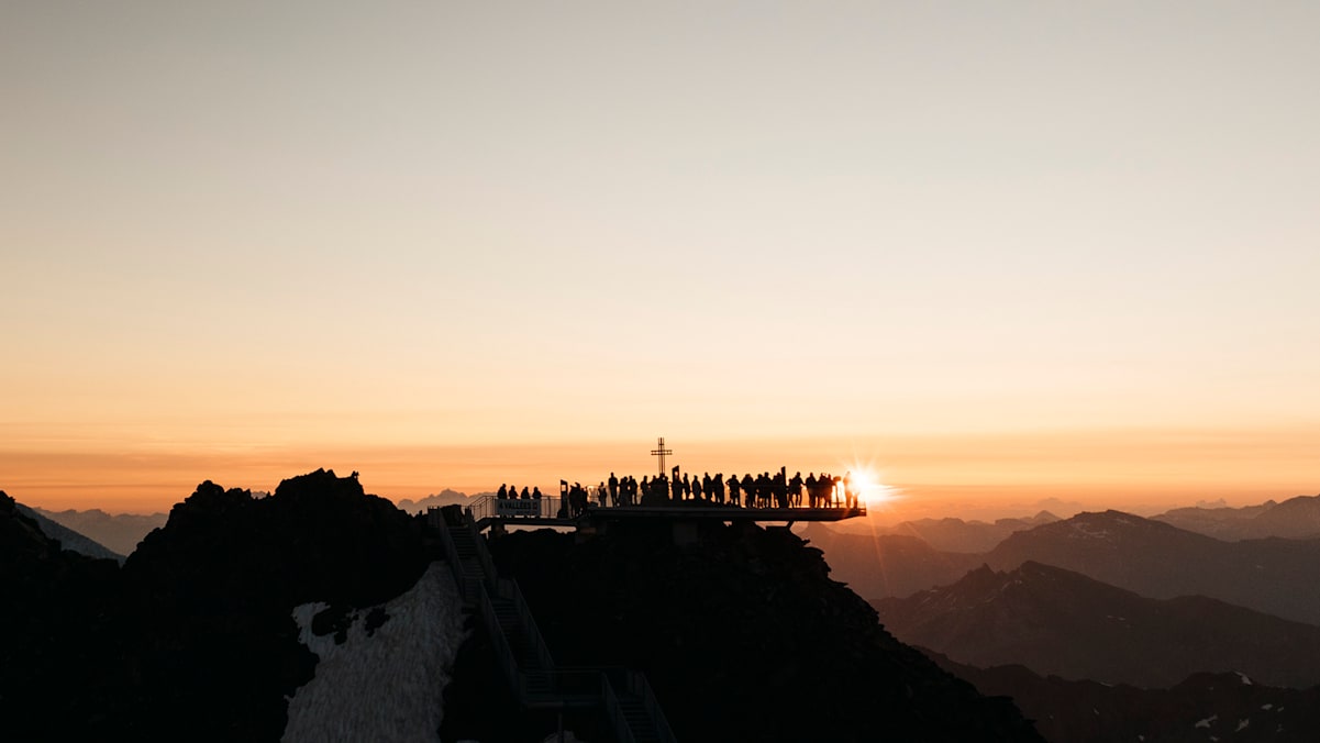 Eine Gruppe von Menschen auf dem Berg Mont Fort schauen sich den Sonnenaufgang an.