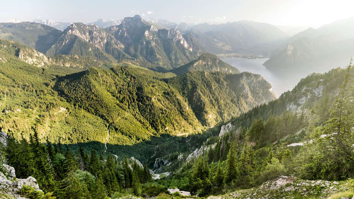 Blick vom Traunstein Richtung Süden – im Hintergrund die „Schlafende Griechin“, der Erlakogel (1.575 m), dahinter das Tote Gebirge. Im Tal die Gemeinde Ebensee am Südende des Traunsees.