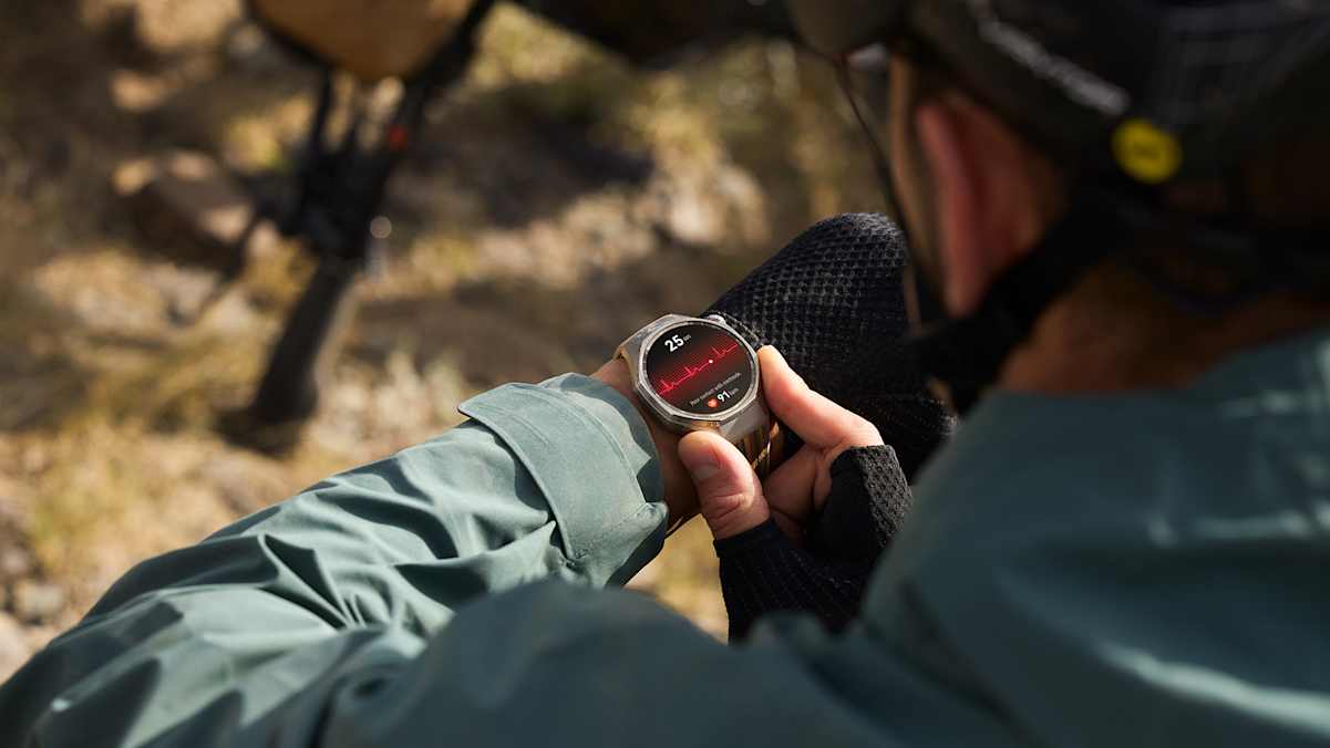 Eine Person überprüft im Freien auf ihrer HUAWEI Watch GT 6 Pro den Herzfrequenzverlauf. Die Smartwatch zeigt ein EKG-ähnliches Diagramm auf einem hellen AMOLED-Display, während im Hintergrund ein Fahrrad zu sehen ist.