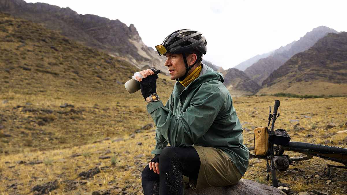 Mountainbiker mit HUAWEI WATCH GT 6 trinkt Wasser bei einer Pause im Gebirge – robuste Smartwatch für Sport und Natur.