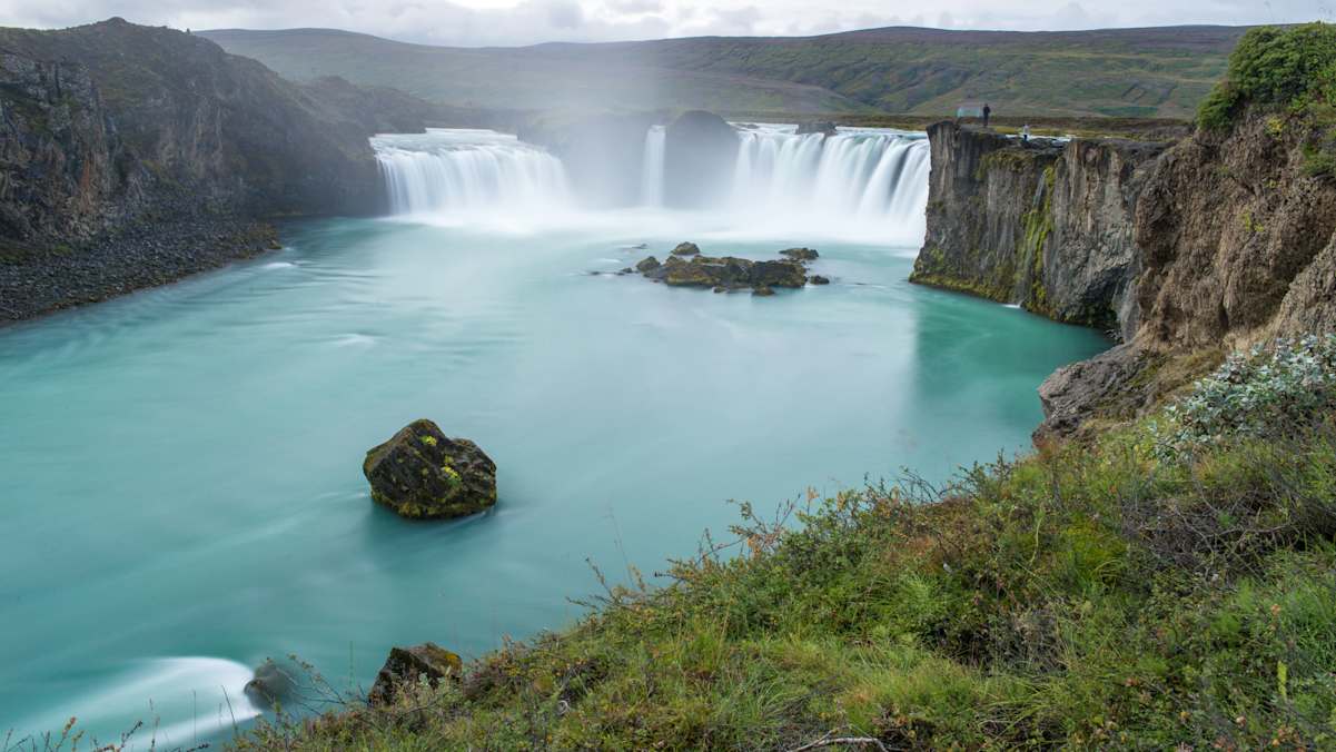 Der 158m breite Godafoss mit hellblauem Wasser und Wasserfall in karger Gesteinslandschaft