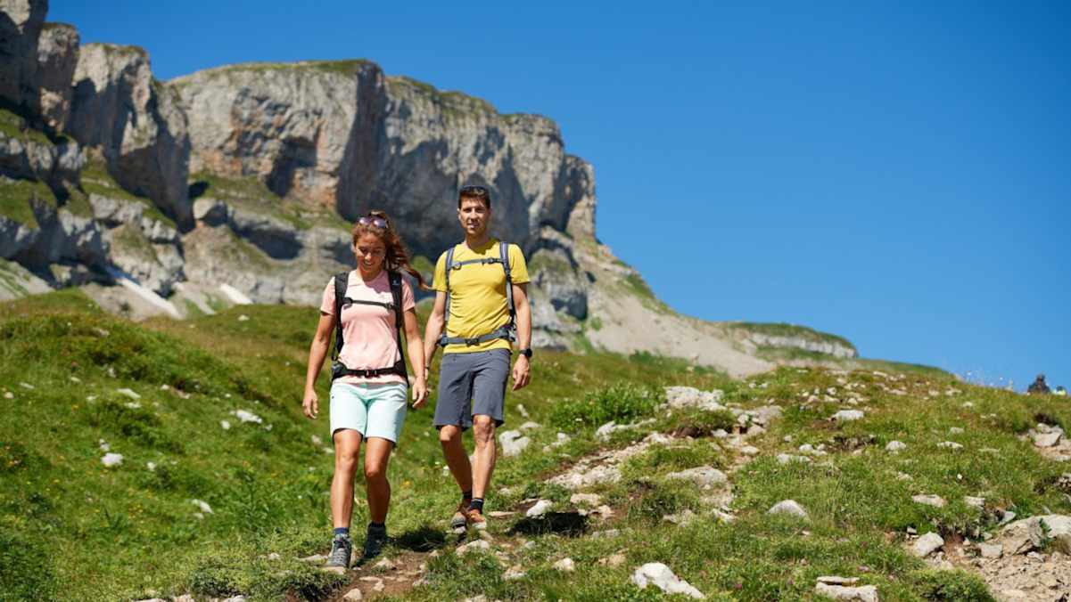 Zwei Wanderer im Abstieg vor einem Berg.