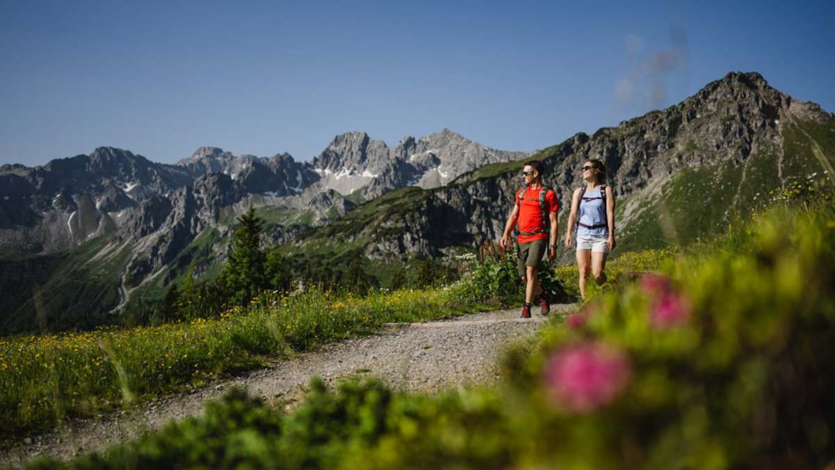 Zwei Wanderer schlendern über einen aussichtsreichen Höhenweg.