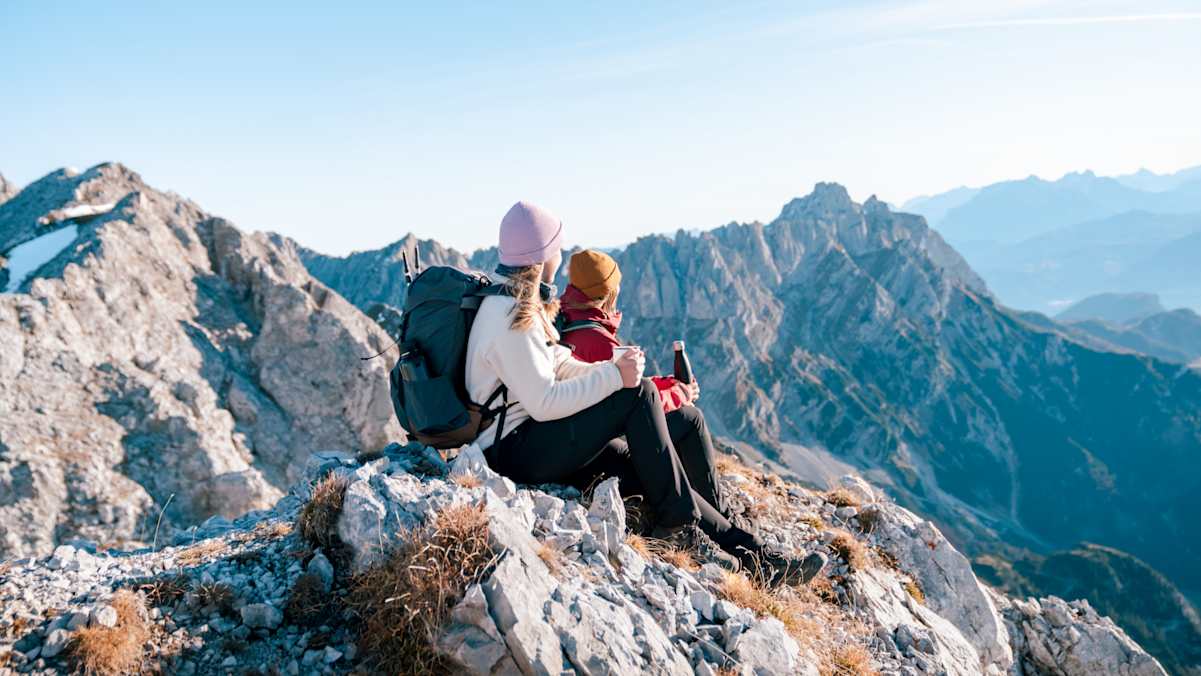 Zwei Mädchen sitzen am Gipfel und genießen eine Pause.