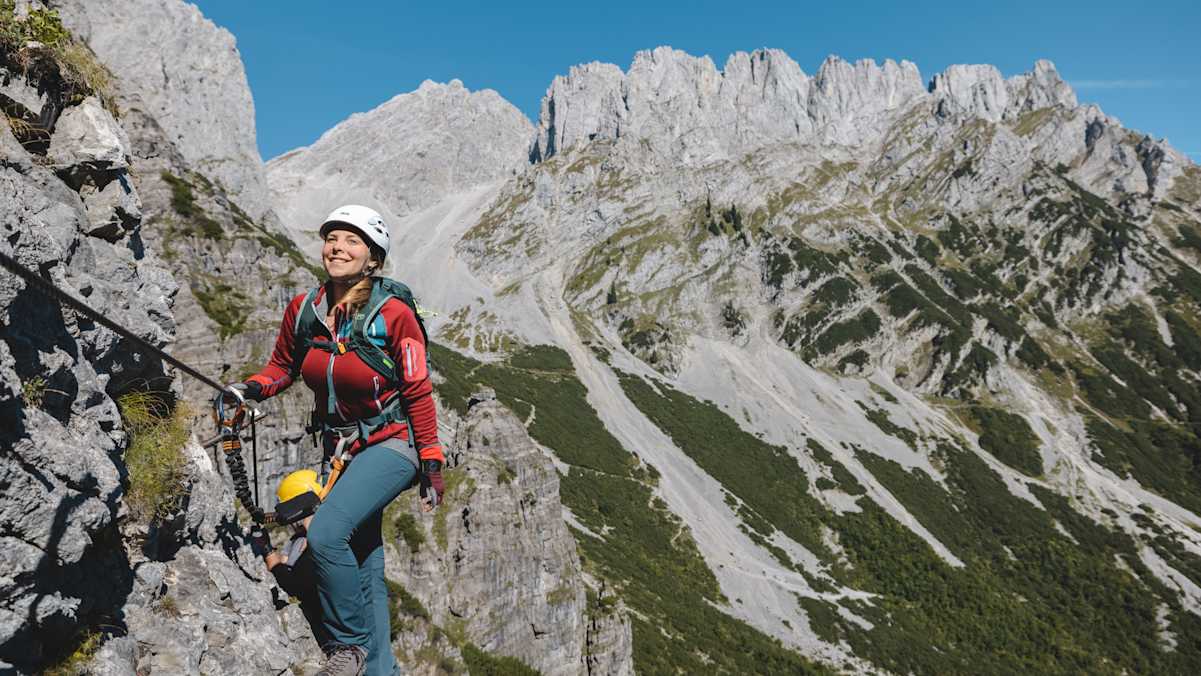 Ein junges Mädchen steigt einen Klettersteig empor.