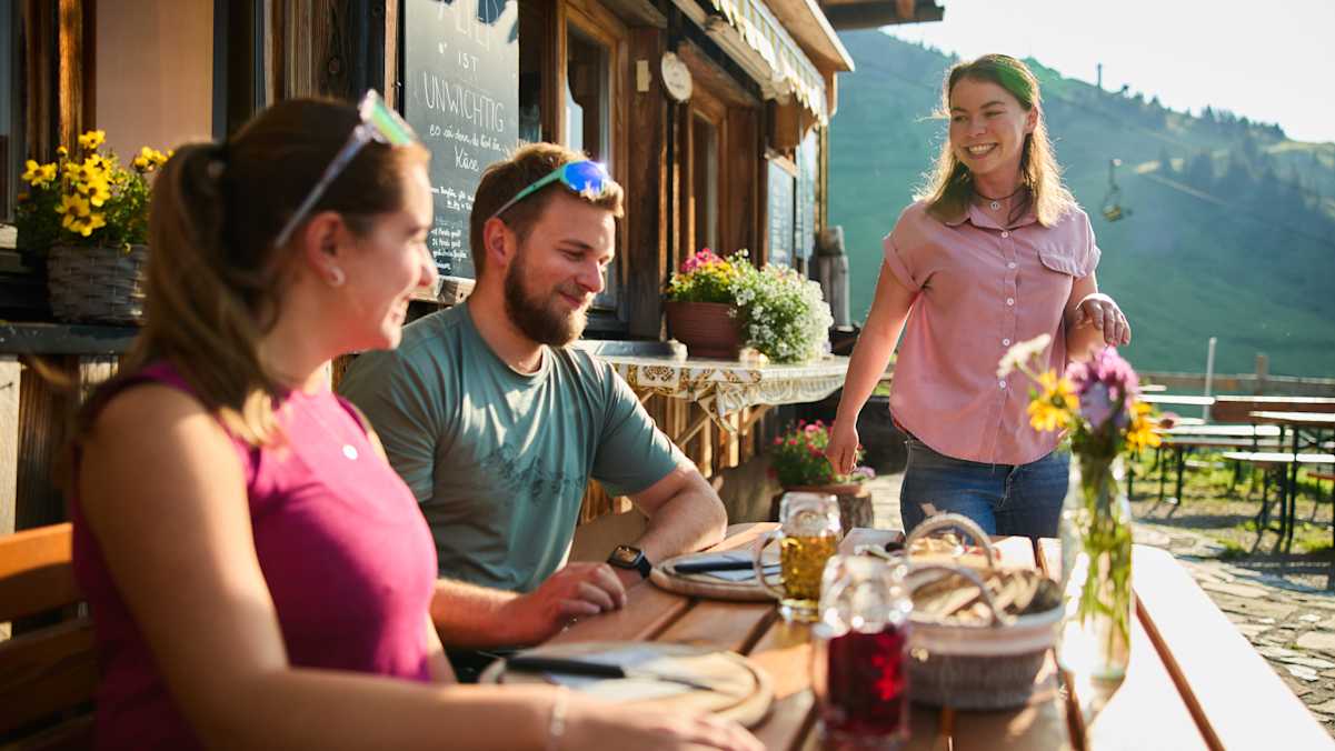 Zwei Wanderer jausnen auf einer Alpe.