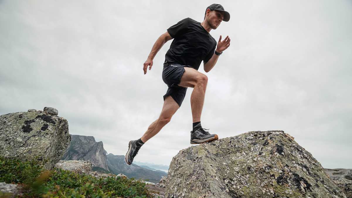 Ein Trailrunner springt mit einem Fuß auf einen Stein im Gebirge. Die Schuhe, die er dabei trägt sind die neuen LOWA AMPLUX 2 GTX.