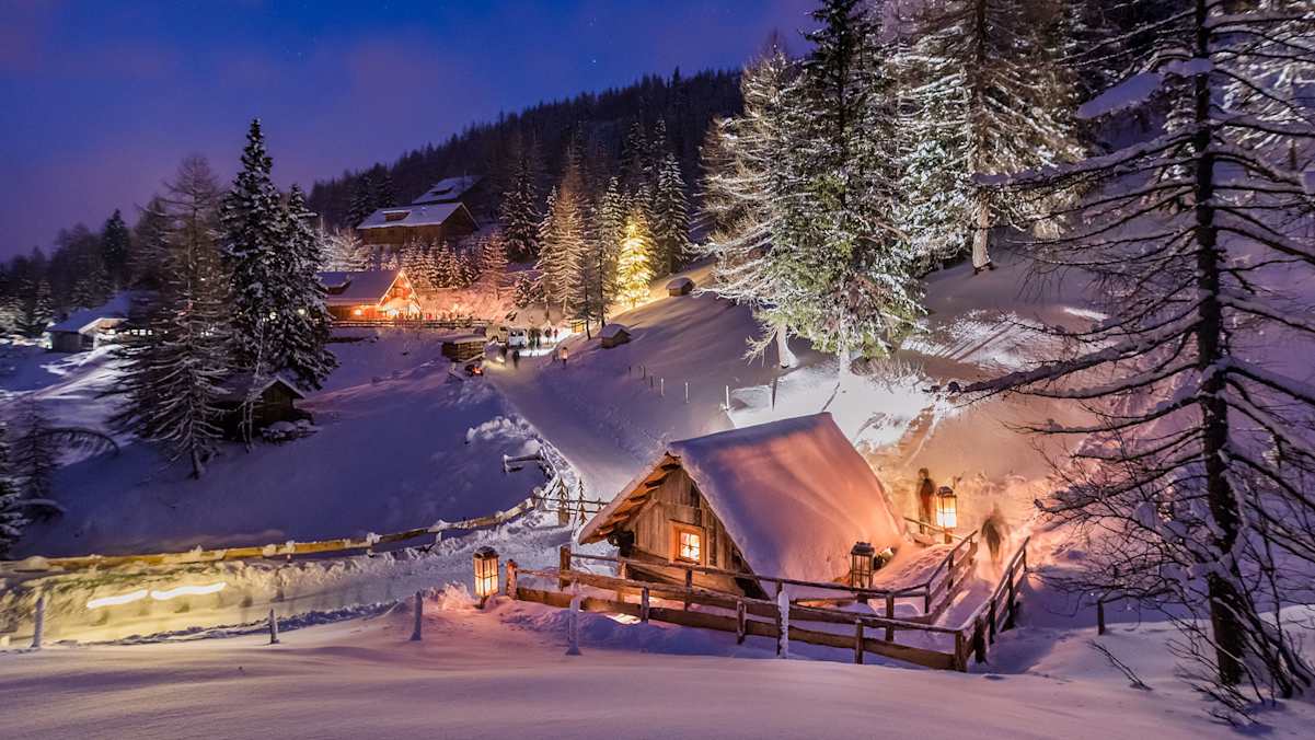 Ein mit Lampen erleuchtetes Bergdorf in der Nacht.