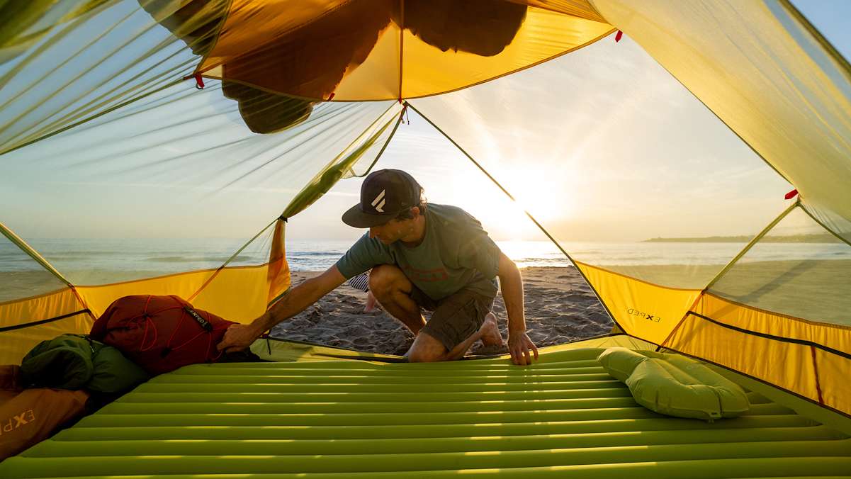 Ein Camper legt seine Matte im Zelt auf.
