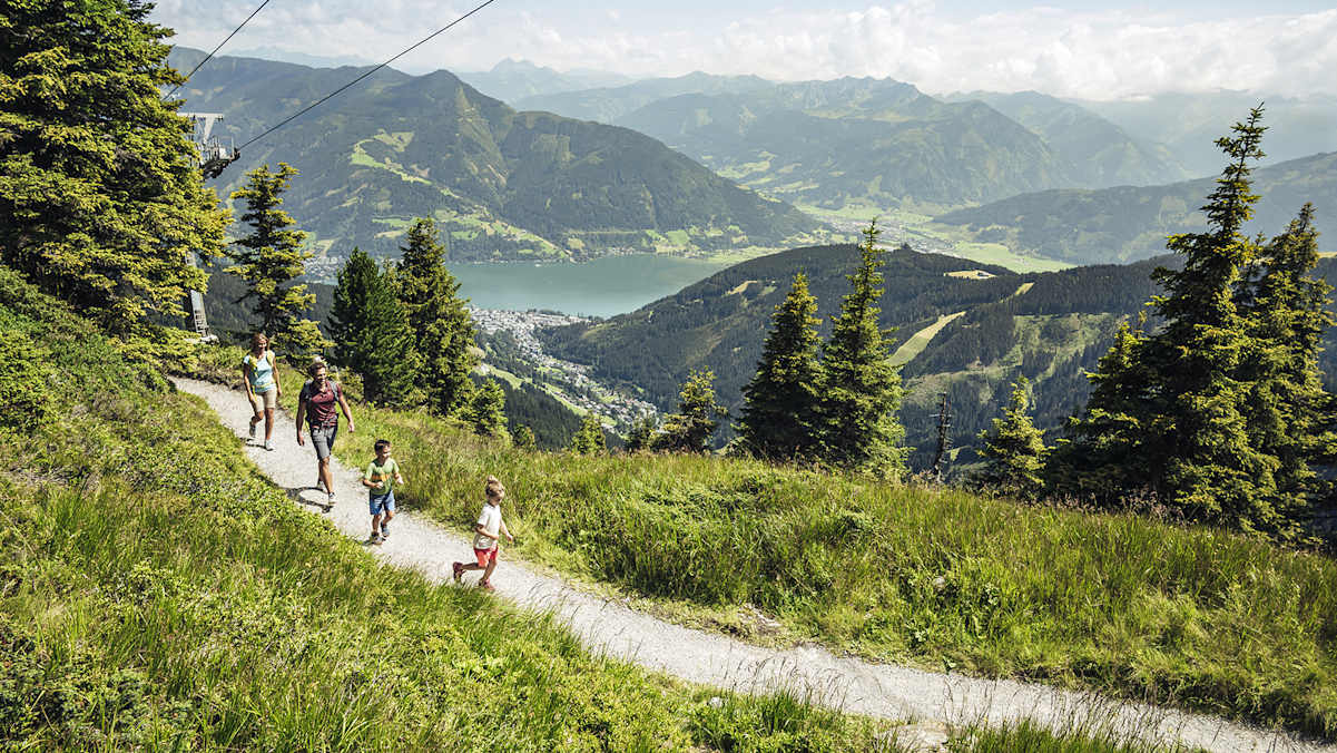 Ein Mann und eine Frau wandern mit ihren zwei Kindern auf die Schmittenhöhe.