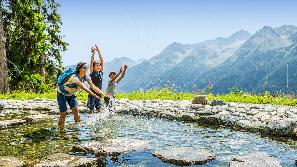 Eine Mutter und zwei Kinder planschen im Sunny Mountain Erlebnispark in Kappl.