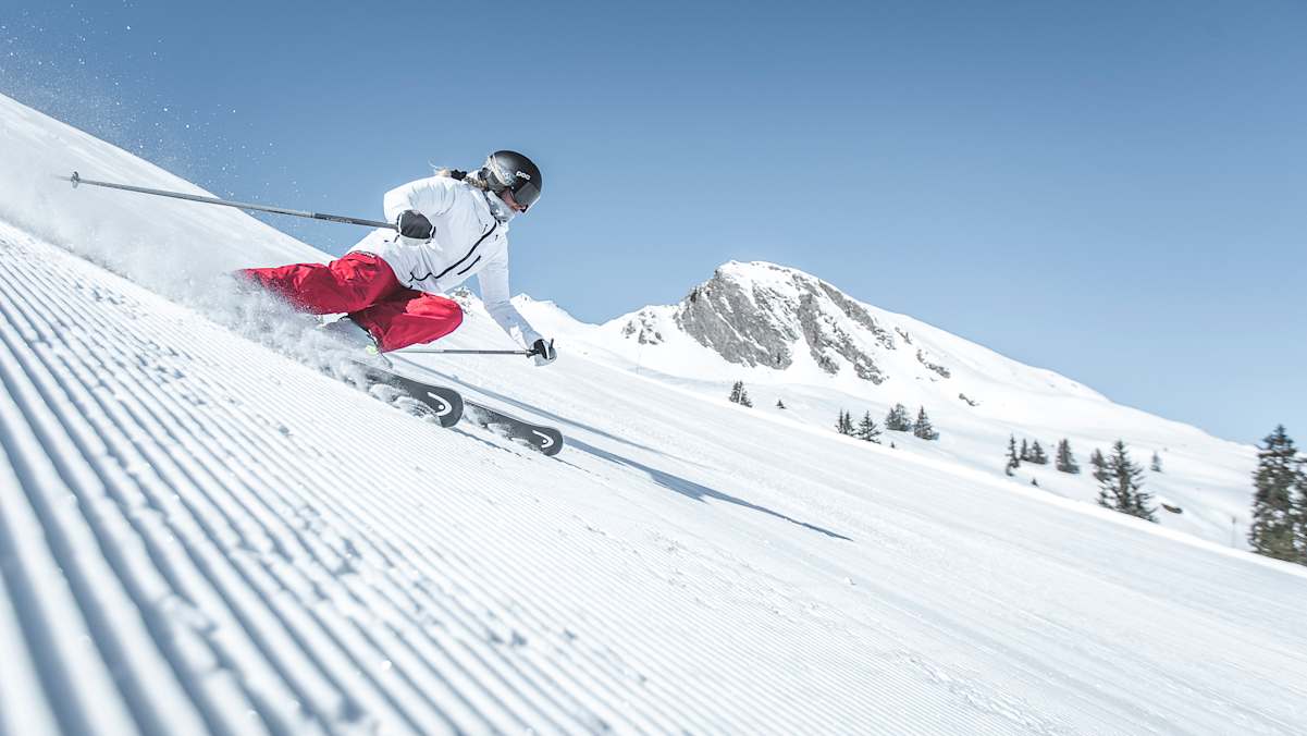 Eine Skifahrerin fährt eine perfekt präparierte Piste hinunter.