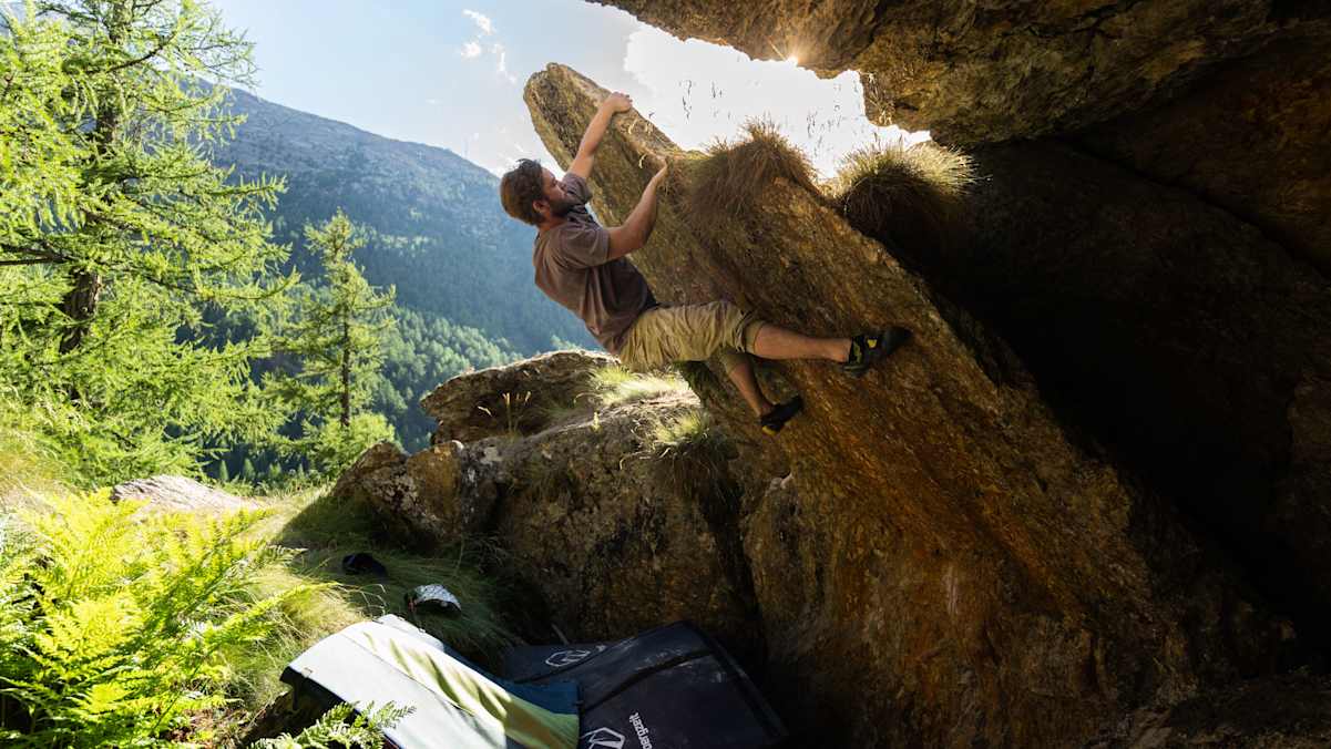 Boulderer beim Bouldern an einem Feld bei Sonnenaufgang in Saas Fee