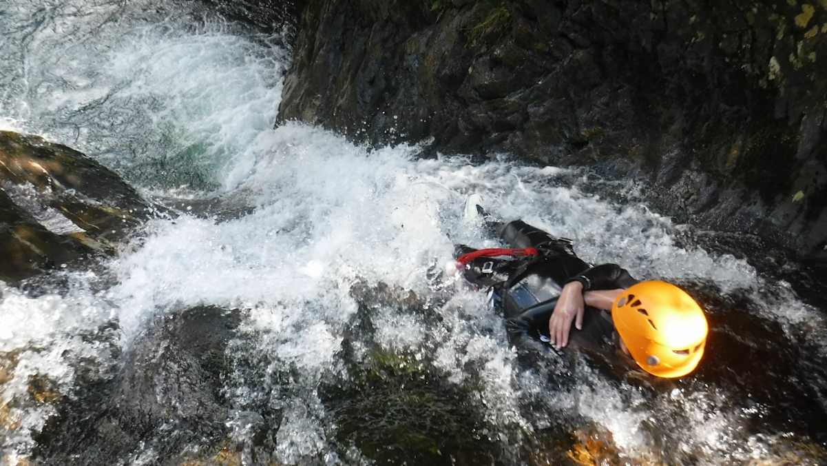 Wasserfall und Schlucht zwischen Felsen mit person beim Abseilen während des Canyonings