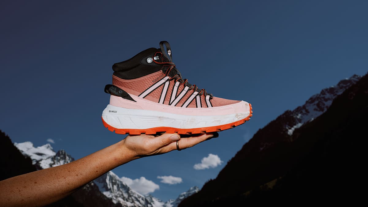 Frau hält Wild Hike Wanderschuh in Rosatönen in ihrer Hand, um ihn zu präsentieren.