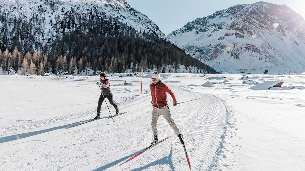 Eine Frau und ein Mann auf ihren Langlaufskiern in der verschneiten Natur Merans.