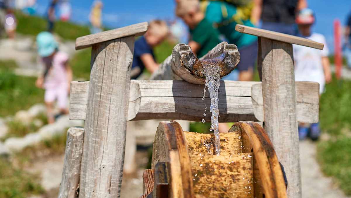Spielerische Elemente wie das Wasserrad machen den Burmiweg zum Erlebnis für Groß und Klein.