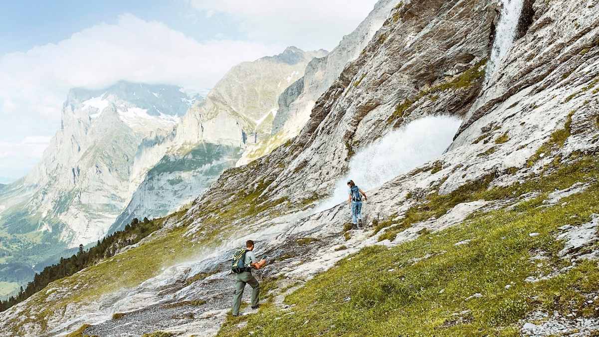 Bergsteiger vor einem Wasserfall.