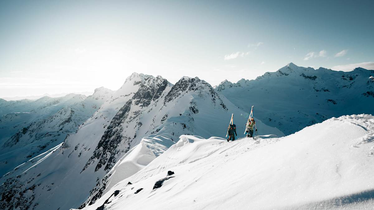 Zwei Skitourengeher vor einem weißen Bergpanorama