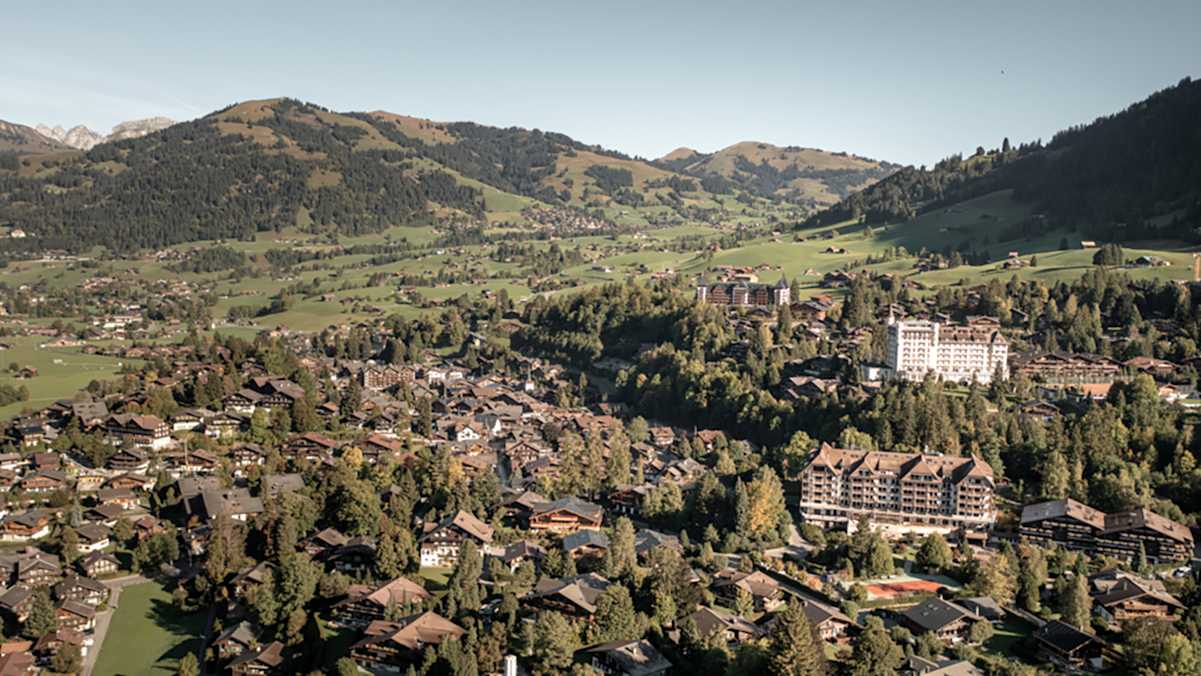 Luftaufnahme von Gstaad mit Blick auf die umliegende Berglandschaft.