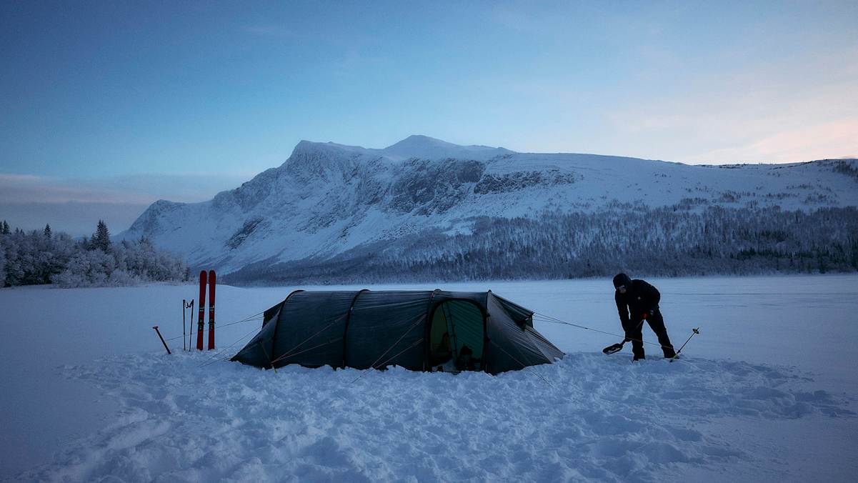 Wintercamping in verschneiter Berglandschaft, perfekt ausgerüstet mit Haglöfs Outdoor-Bekleidung und -Ausrüstung.