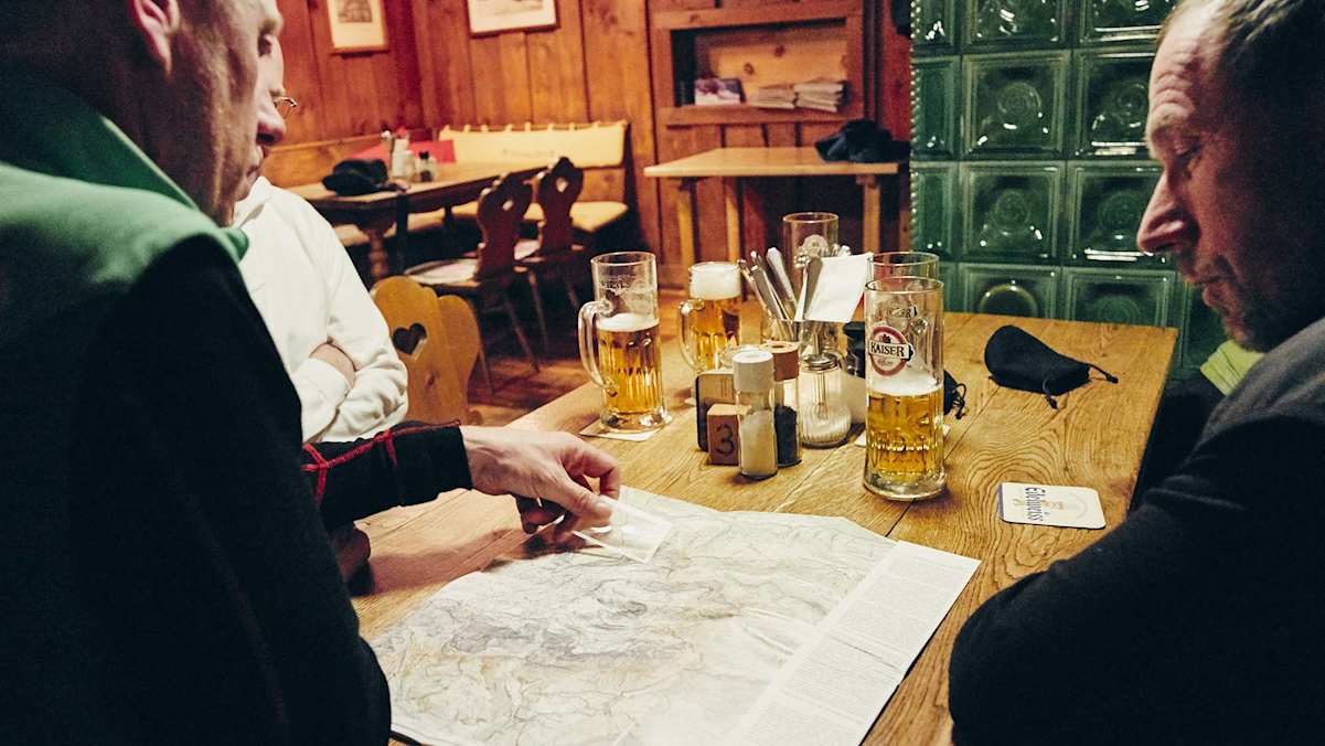 Die Crew sitzt vor einen Karte in der gemütlichen Stube der Ostpreußenhütte.