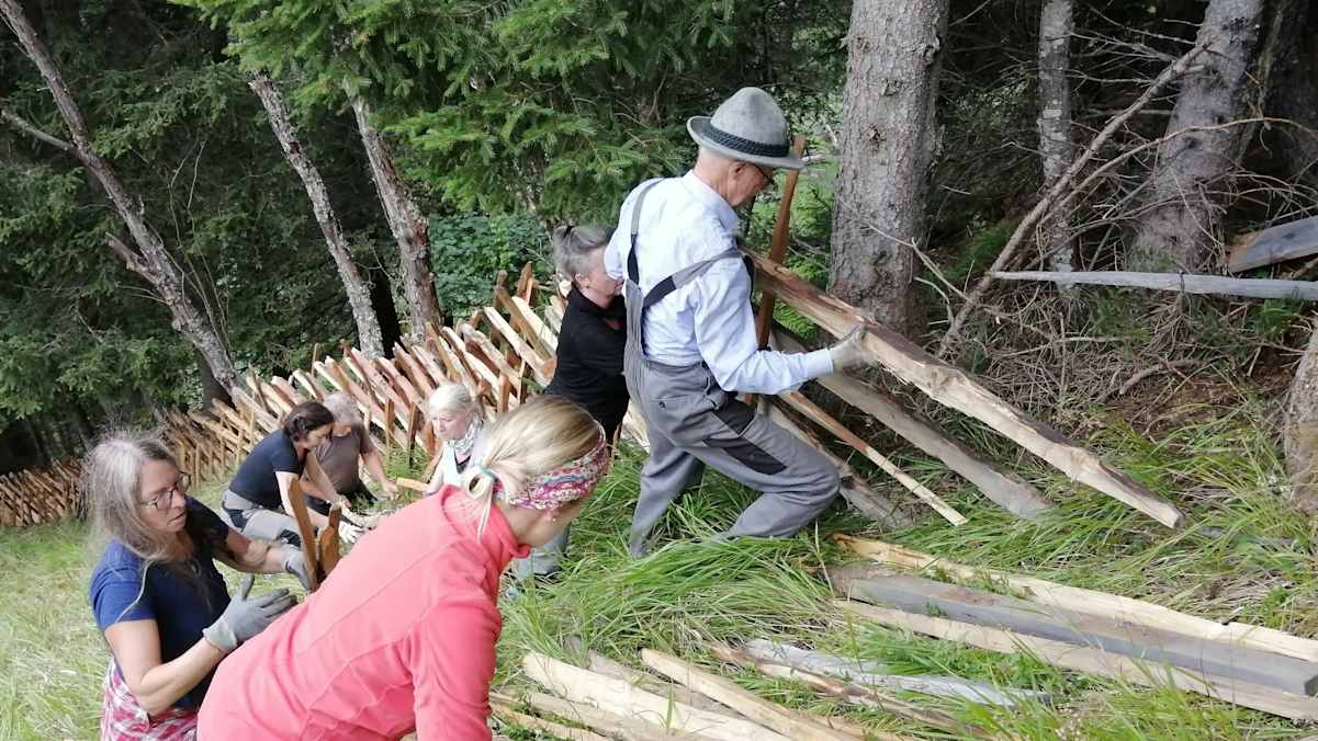 Menschen errichten gemeinsam einen Zaun.