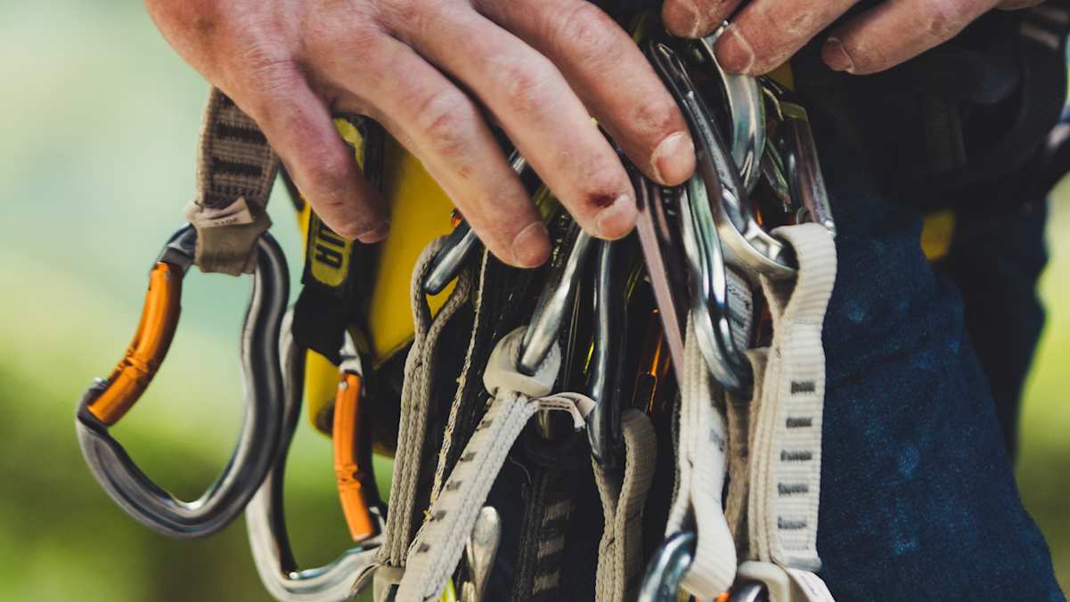 Duzende Karabiner baumeln am Klettergeschirr.