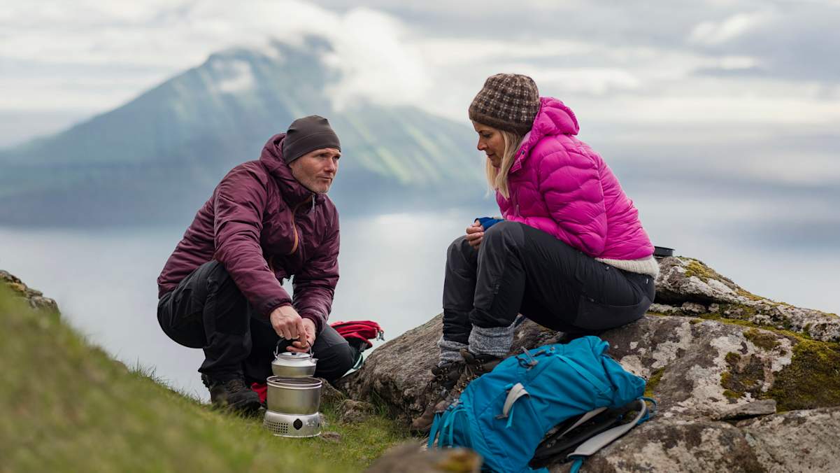 Zwei Personen sitzen mit dicken Jacken vor einem See.