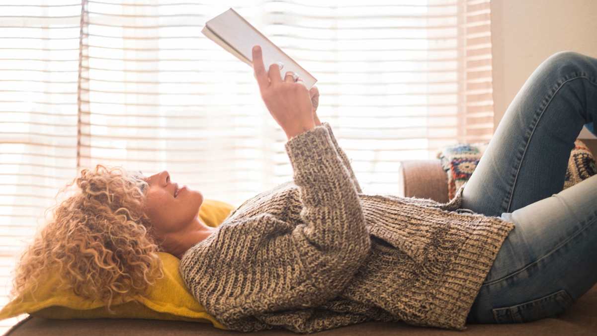 Frau liest Buch im Liegen