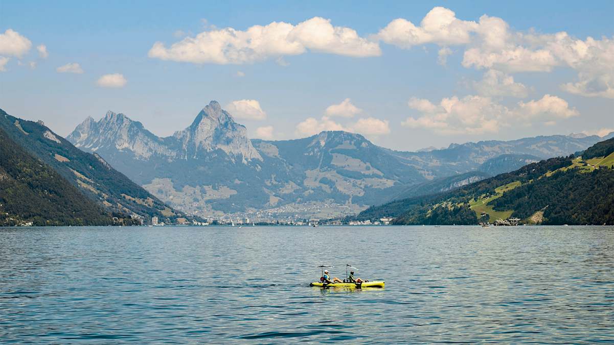Zwei Paddler am See, dahinter atemberaubendes Bergpanorama.