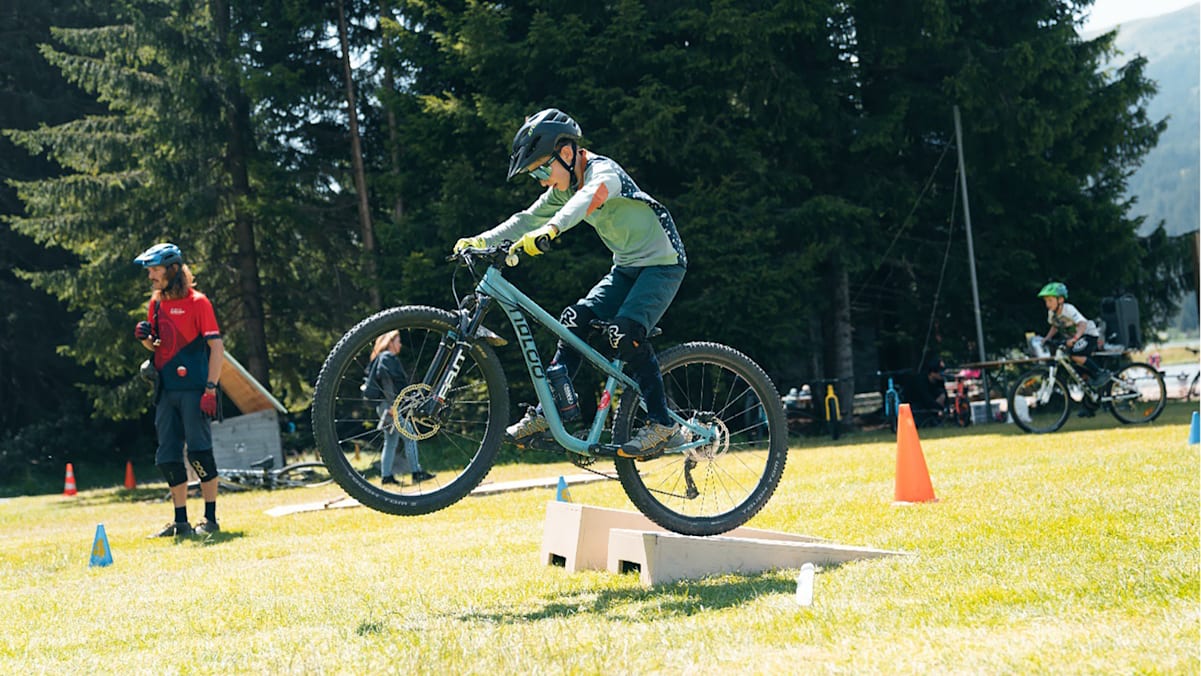 Ein Kind übt im Sommer-Rad-Kurs in der Schweiz Tricks mit dem Moutainbike.