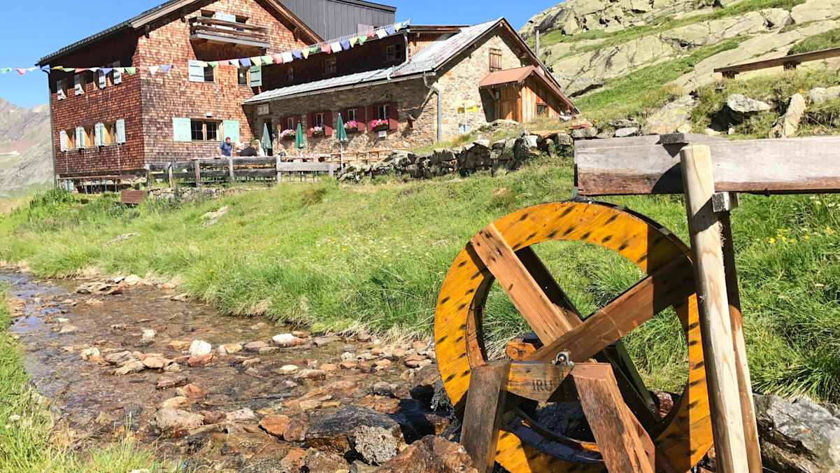 Viele Hütten gewinnen ihre Energie aus Kleinwasserkraftwerken. Symbolhaft mit diesem schönen Holzwasserrad vor der Edmund-Graf-Hütte im Verwall dargestellt.