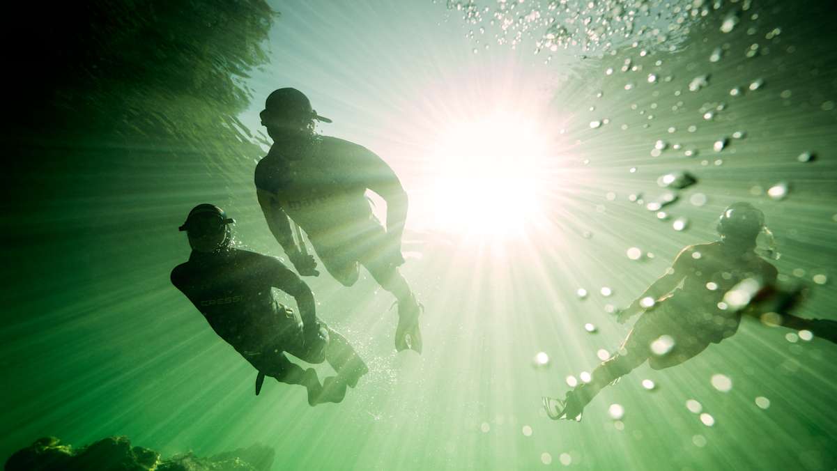 Drei Schnorchler in der Tiefe.