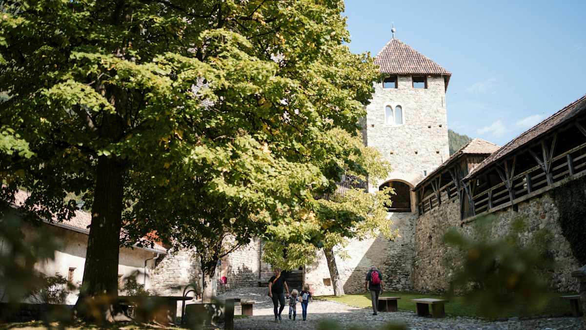 Das Schloss tirol in Südtirol mit Bäumen und Wanderern