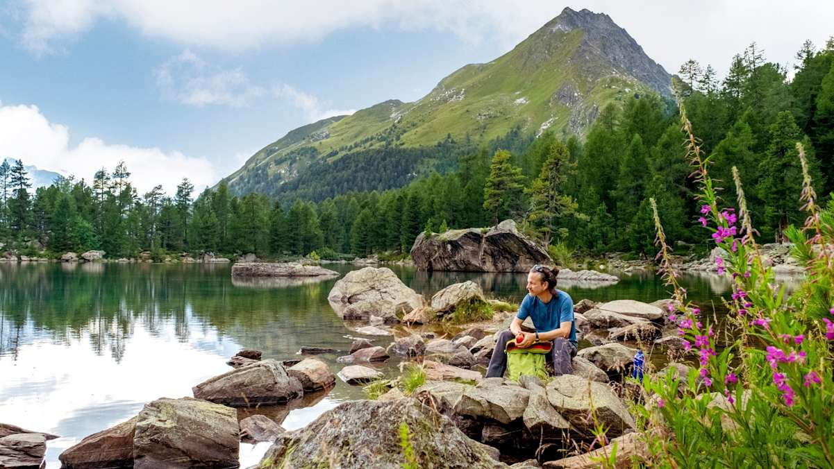 Ein Wanderer ruht sich am Wasser aus.