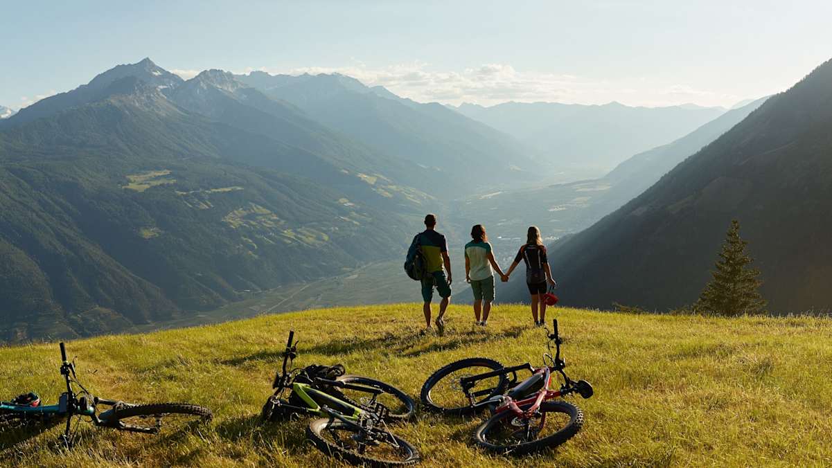 drei Mountainbiker beim Rasten während Sonnenuntergang am Vigiljoch in Südtirol