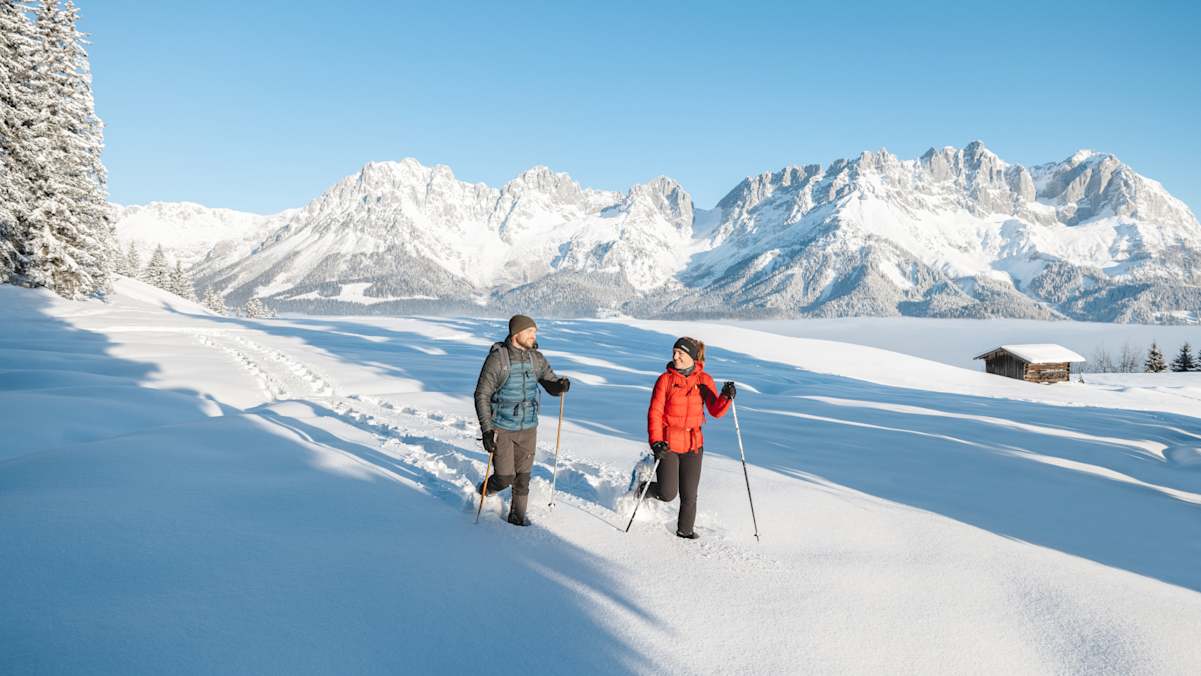 Ein Pärchen wandert mit Schneeschuhen durch die tief verschneite Bergwelt des Wilden Kaisers.