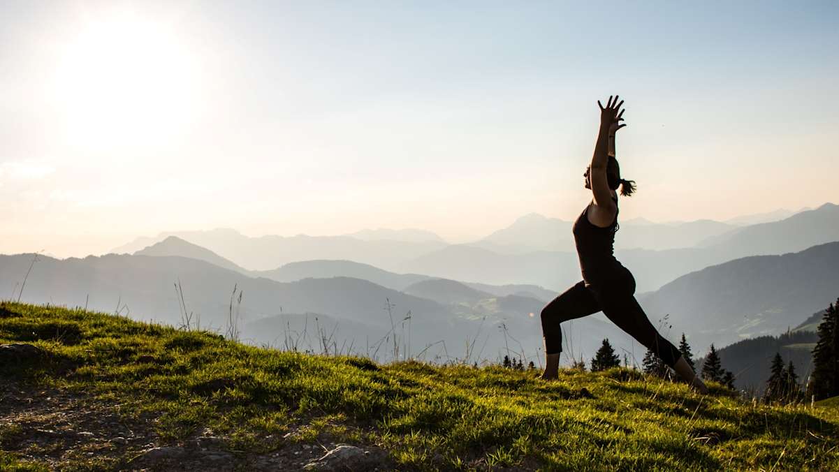 Eine Frau macht Yoga vor einer Bergkulisse.