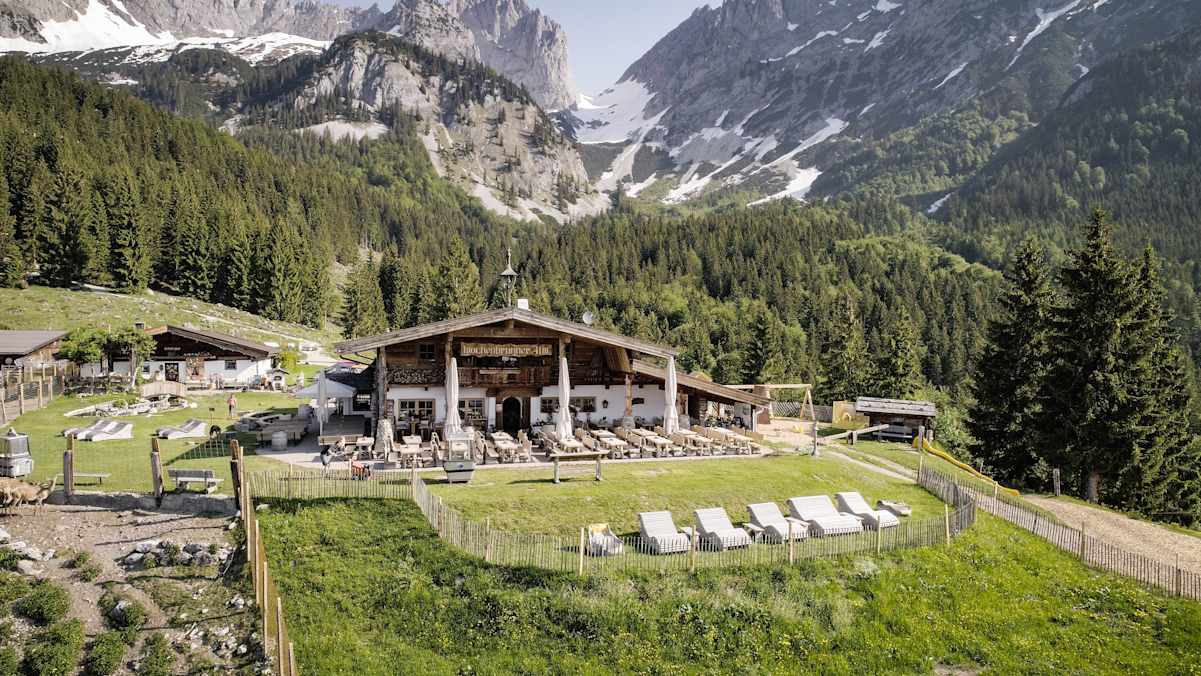 Holzliegen laden auf der großen Sonnenterrasse der Wochenbrunner Alm zum Relaxen ein.