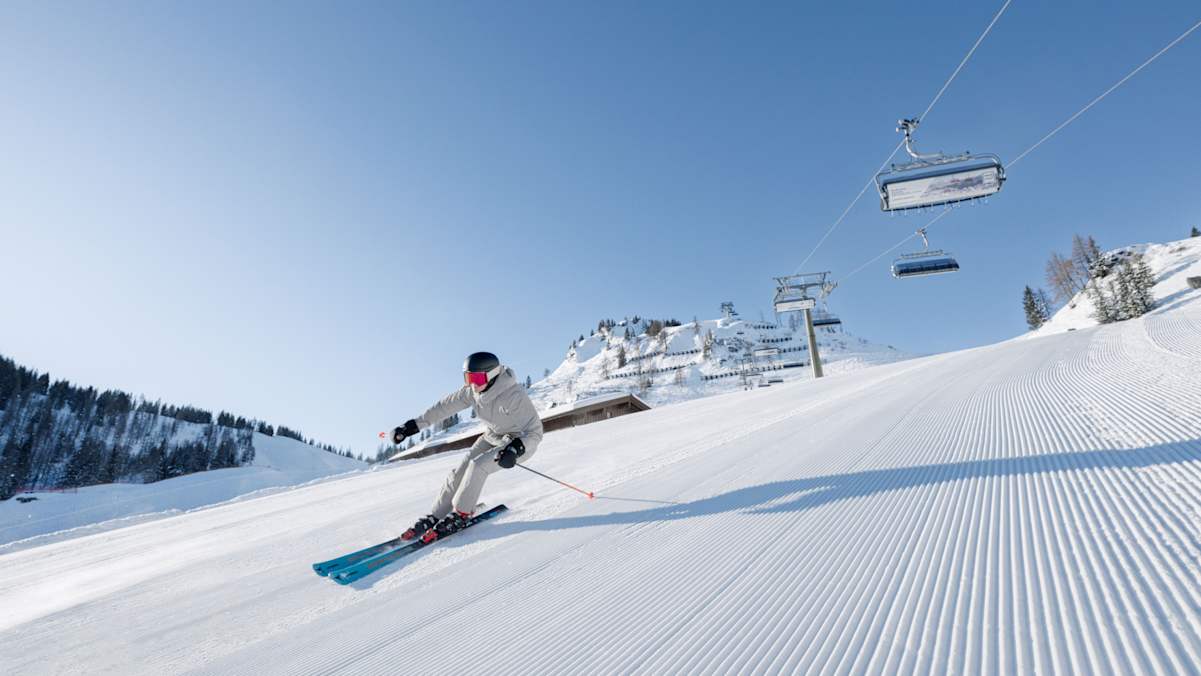 Ein Skifahrer carvt auf einer frisch präparierten Piste auf der Hermann Maier Tour im Snowspace Salzburg.