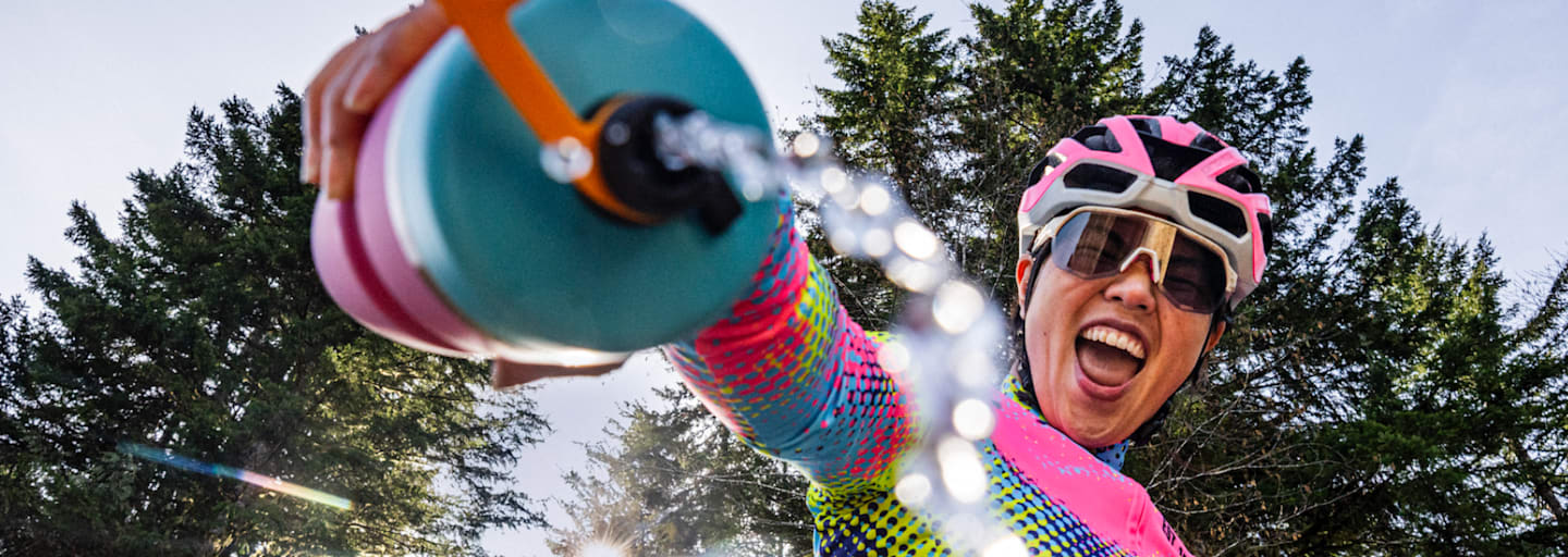 Radfahrerin mit Edelstahl-Trinkflasche von Bivo im Wald – plastikfreie, nachhaltige Hydration für Outdoor-Abenteuer.