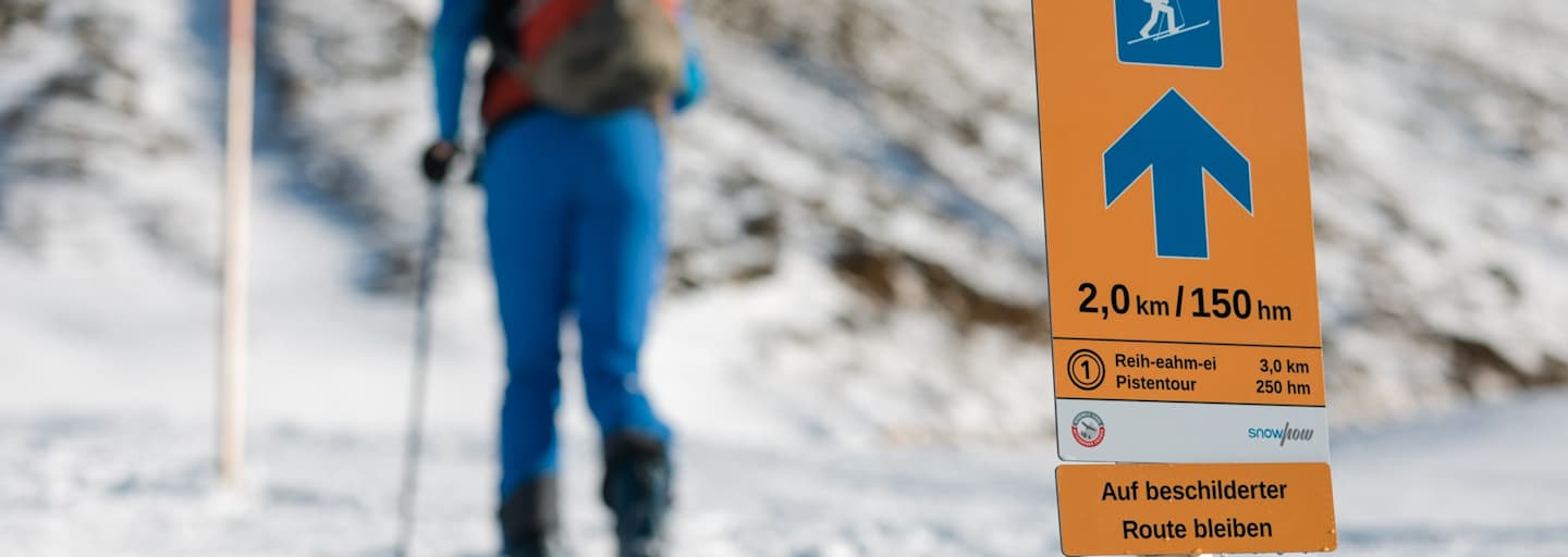Das Pistentourenleitsystem des Landes Tirol mit orangen Hinweisschildern zeigt den sicheren Weg nach oben.