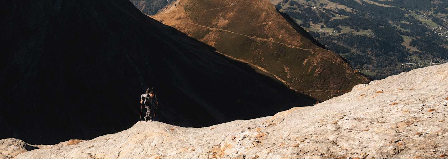 Ein Alpinist steigt einen Berg mit zwei Stöcken und der Haglöfs L.I.M ZT 2.0-Serie hinauf.