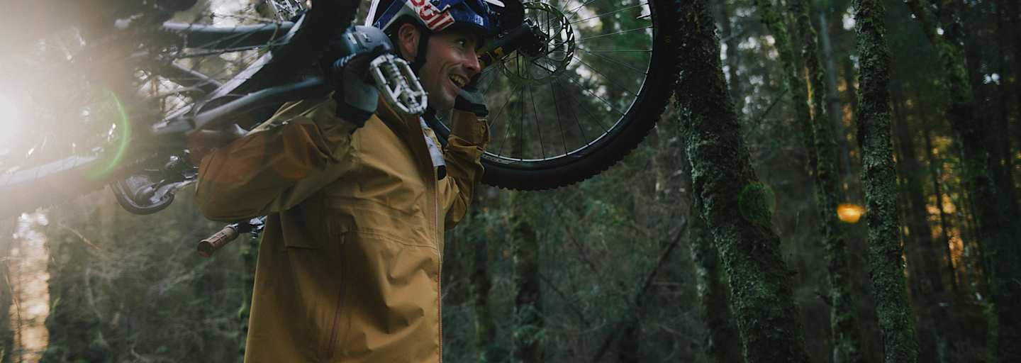 mann hat sein mountainbike auf den schultern, im wald