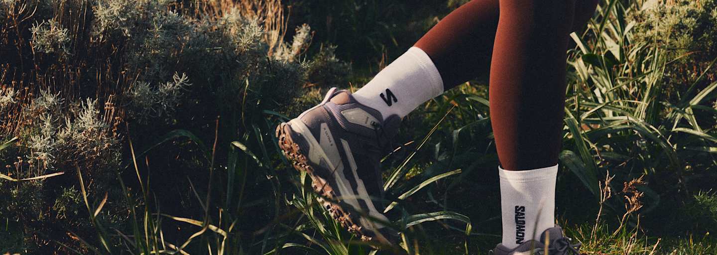 füße in salomon ausrüstung im gras beim wandern