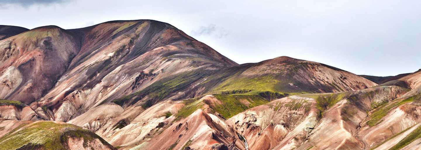 Landmannalaugar: Einsamer Wanderer in der Vulkanlandschaft von Landmannalaugar im Hochland. Buntes Rhyolith-Gestein teils mit Moos überwachsen.