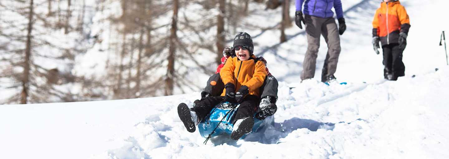Zwei Kindern beim Bobfahren in der Natur.