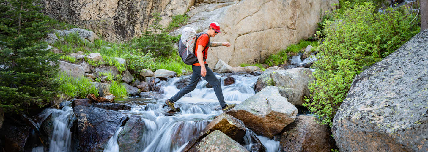 Rab Muon 50L Wanderrucksack mann geht über wasserfall
